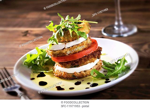A stack of fried aubergine slices, mozzarella and tomato