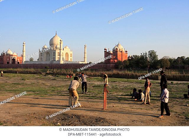Children playing cricket at Taj Mahal Seventh Wonders of World on south bank of Yamuna river , Agra , Uttar Pradesh , India UNESCO World Heritage Site