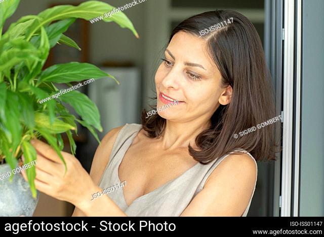 Smiling woman taking care of potted plant