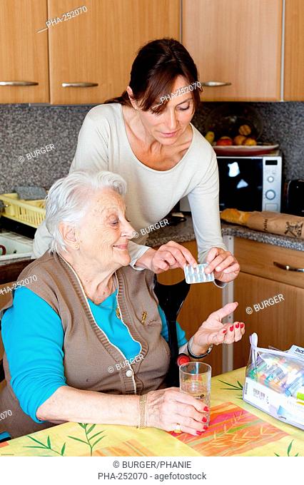 Woman assisting 94 years old woman taking medication