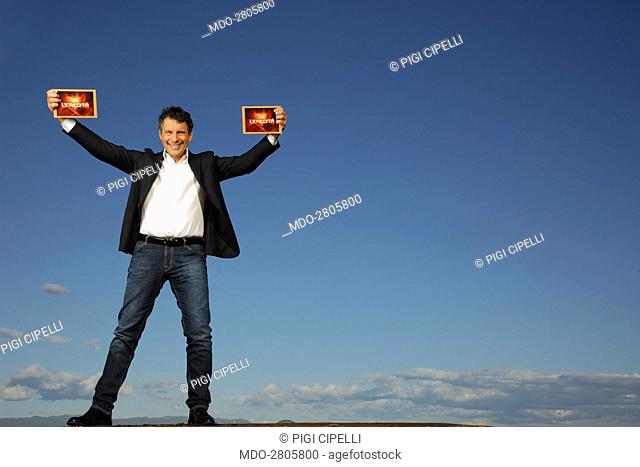 The TV host Fabrizio Frizzi showing two papers in a photocall shooted outside the RAI TV studios where he presents the TV quiz L'eredità. Rome, Italy