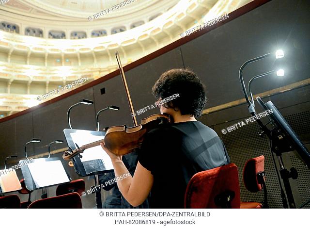 A violinist from the orchestra tuning up during preparations for the performance of Porgy and Bess by George Gershwin at the Semperoper in Dresden, Germany