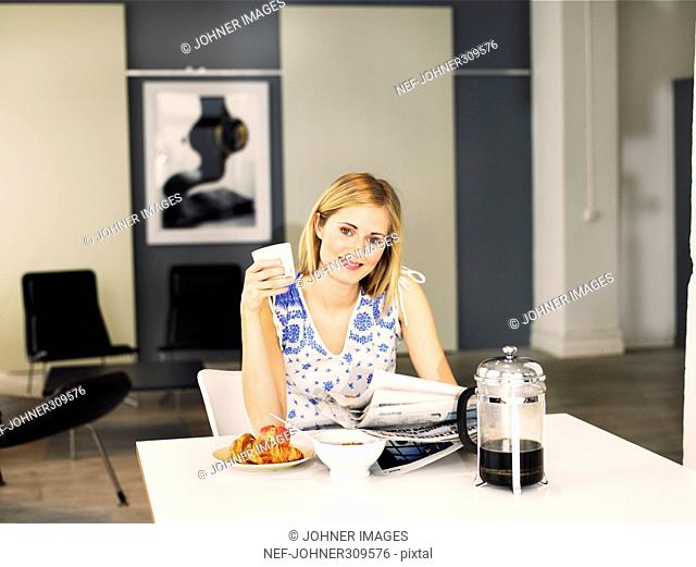 A woman reading the paper during breakfast