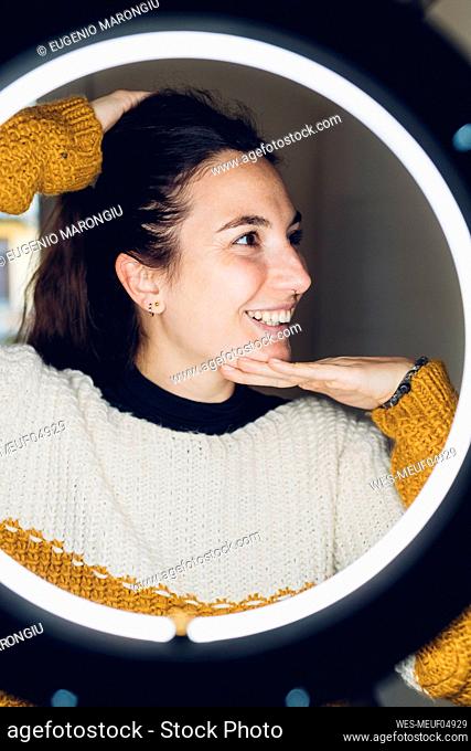 Smiling influencer touching face in front of ring light