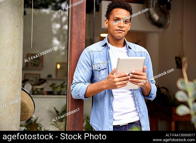 Latin American nursery plant worker holding digital tablet while looking at the camera