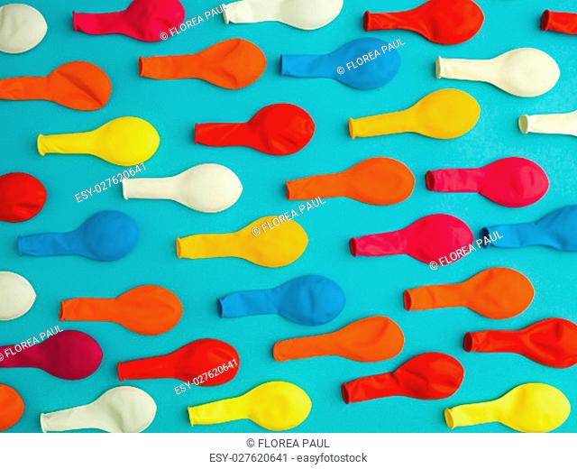 arranged pattern of colourful deflated balloons on a blue background