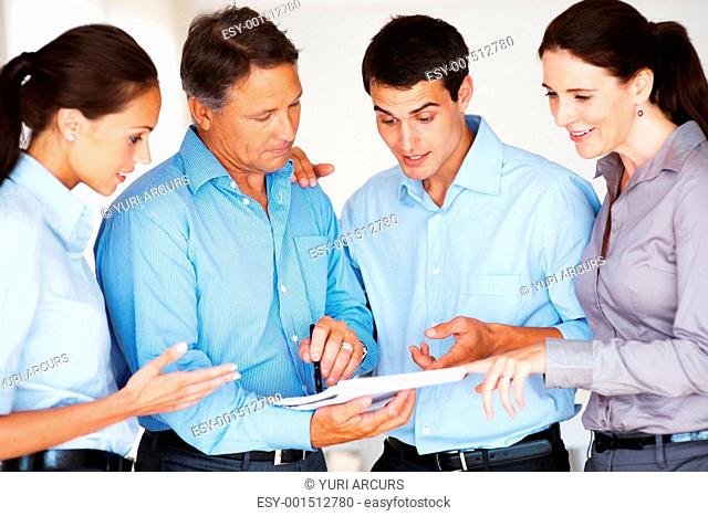 Group of executives discussing business plans with each other with mature executive holding notebook