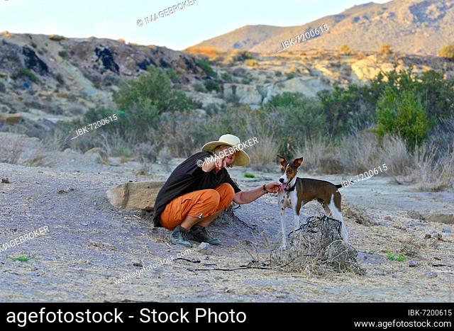 Woman with straw hat squatting talking to her dog, Andalusia, Spain, Europe