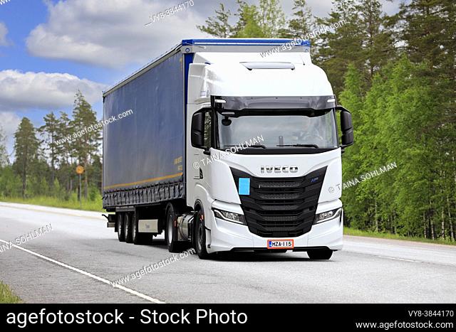 New, white gas-powered Iveco S-Way Natural Power, NP, truck in front of semi trailer on highway 25 on a sunny day. Raasepori, Finland. May 27, 2021