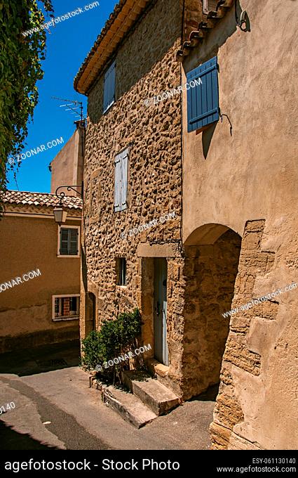 View of typical stone houses with sunny blue sky, in an alley on slope at the historical village of Lourmarin. In the Vaucluse department