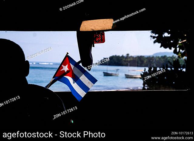 Inside shot of a car with Cuban flag driving towards the sea