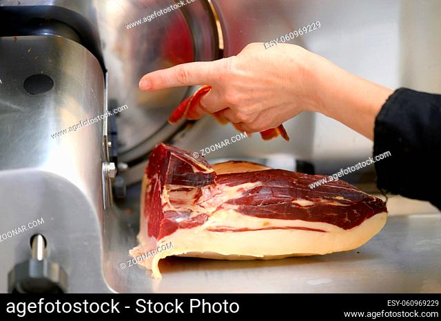 chef wearing using ham slicer machine. High quality photo