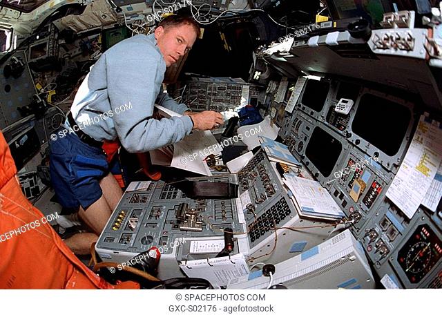 A fish-eye lens on a 35mm camera records Richard A. Searfoss, mission commander, at the commander's station on forward flight deck of the Earth-orbiting Space...