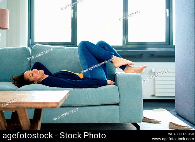 Smiling businesswoman relaxing on sofa in break time at office