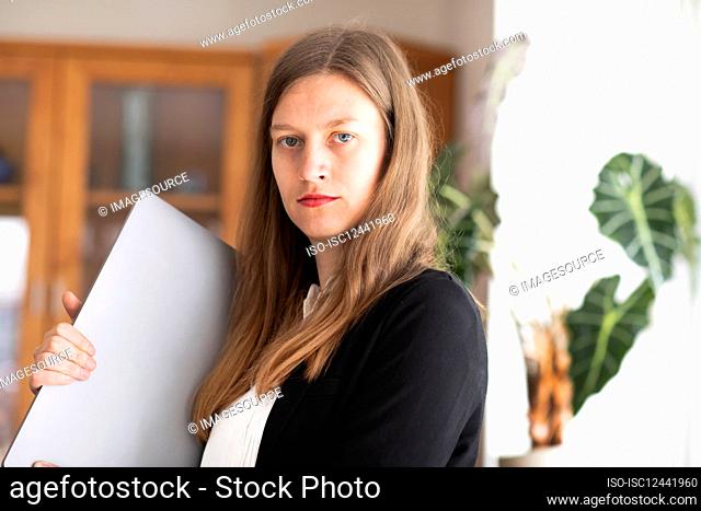 Portrait of young businesswoman holding laptop