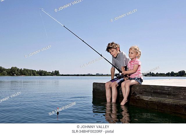Brother and sister fishing on dock