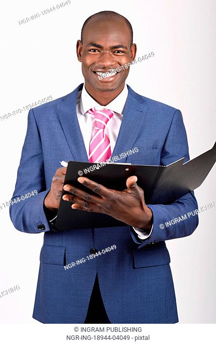 Portrait of black businessman wearing suit and tie smiling on white background with a black folder in his hands. Studio shot