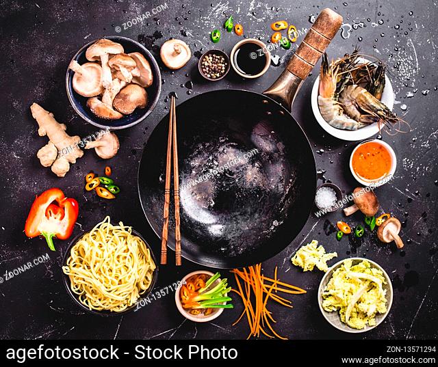 Asian food cooking concept. Empty wok pan, noodles, vegetables stir fry, shrimps, sauces, chopsticks. Asian/Chinese food. Top view