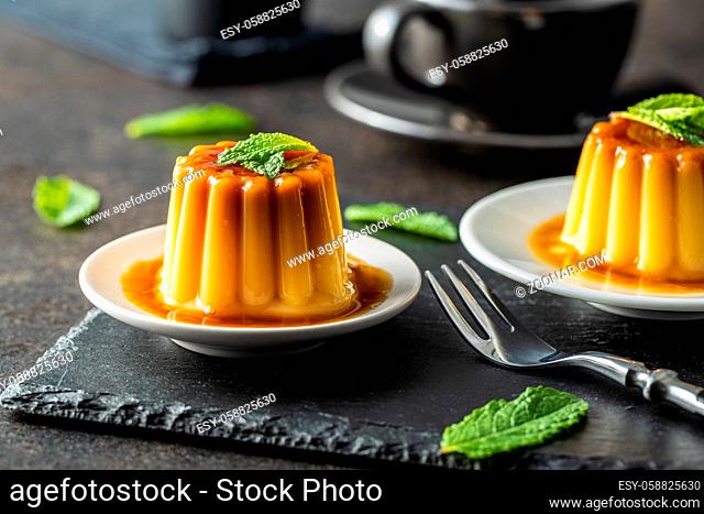 Sweet vanilla pudding. Sweet dessert with caramel topping on black table