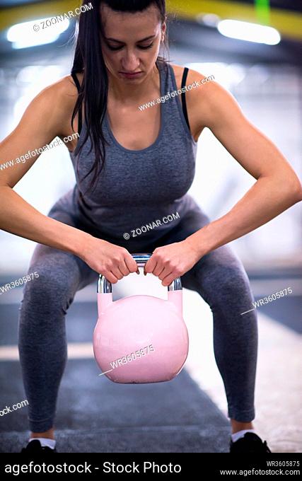 young woman athlete exercise with fitness kettlebell at cross fitness gym