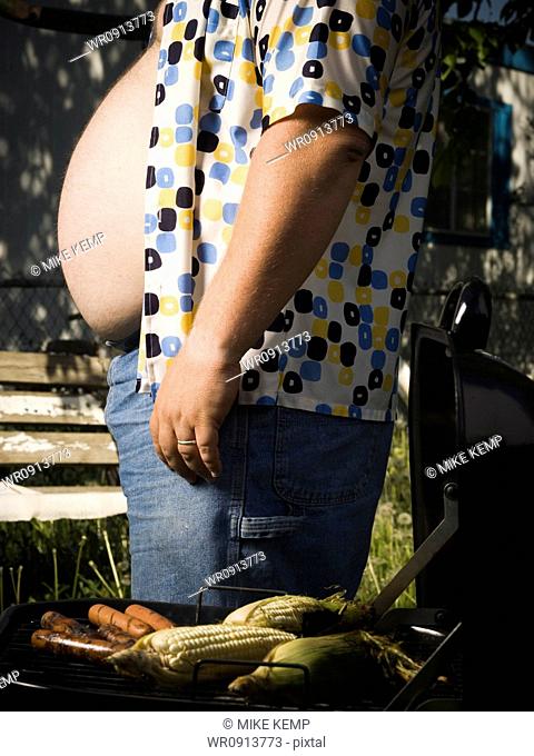 Overweight man by barbecue grill