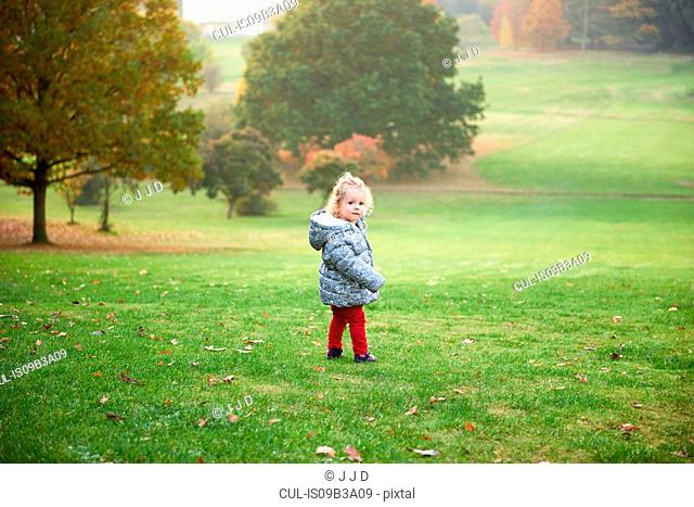 Portrait of female toddler looking over her shoulder in autumn park