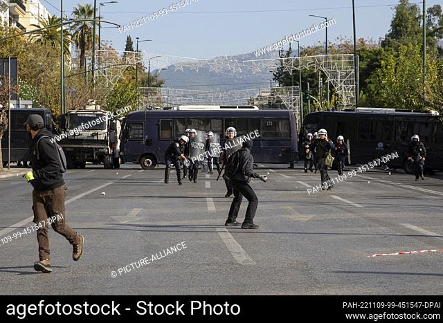09 November 2022, Greece, Athen: A demonstrator throws a stone at riot police officers during a 24-hour general strike in Athens