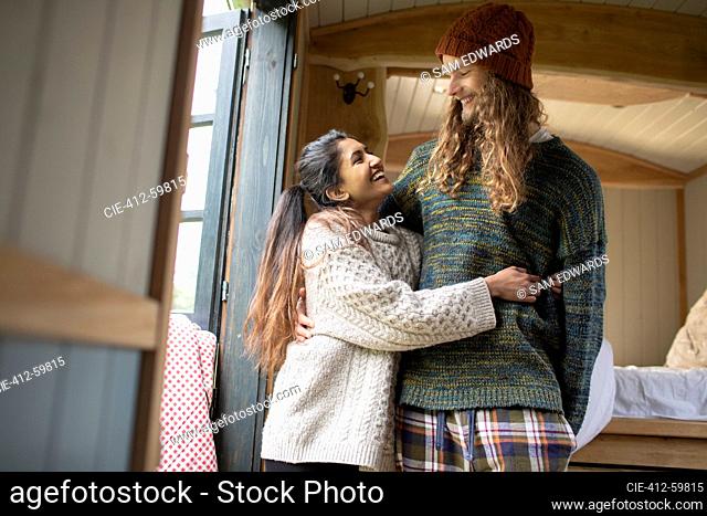 Happy young couple hugging in tiny cabin rental