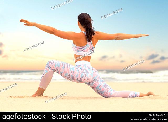 Young beautiful woman practice yoga on sea sand at daytime
