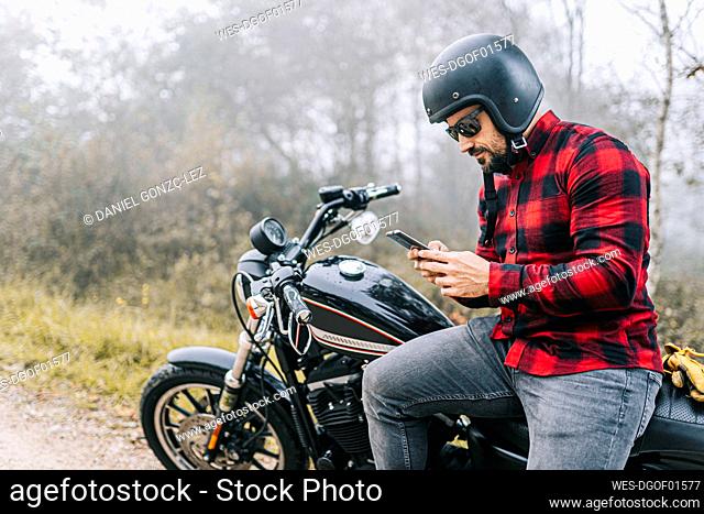Man using smart phone while sitting on motorcycle during road trip