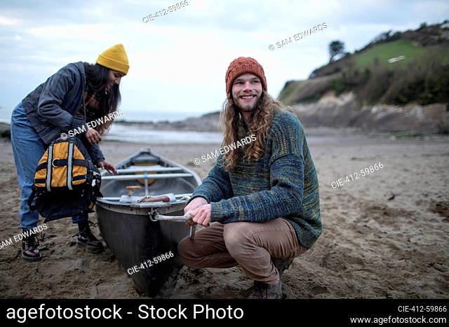 Smiling young couple with canoe on beach