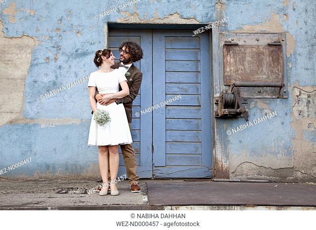 Bridal couple standing in front of blue wooden door