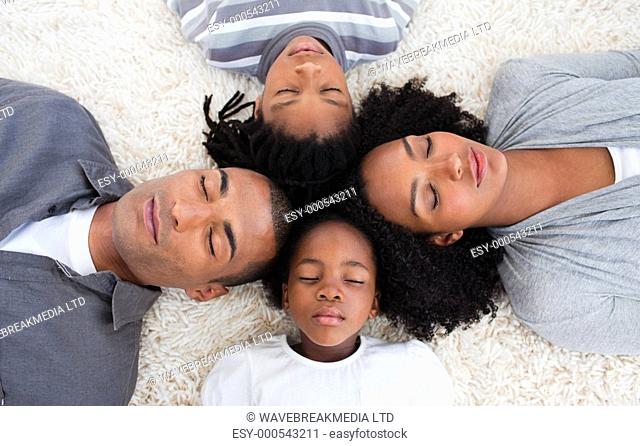 Afro-American family sleeping on floor with heads together in a circle