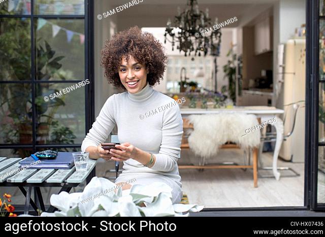 Portrait happy young woman using smart phone on patio