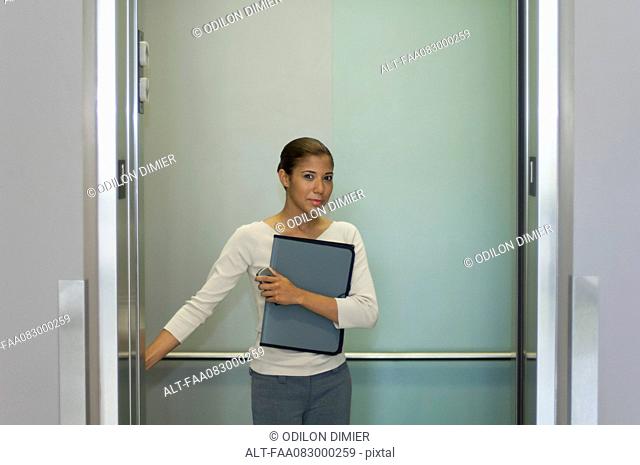 Young woman pushing button in elevator