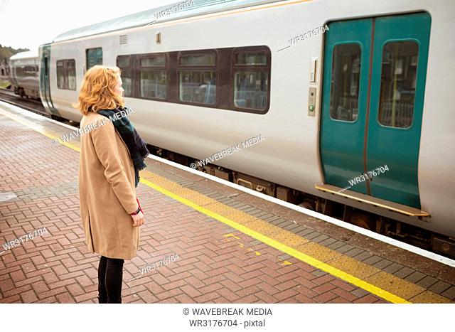 Young woman standing on platform in front of running train