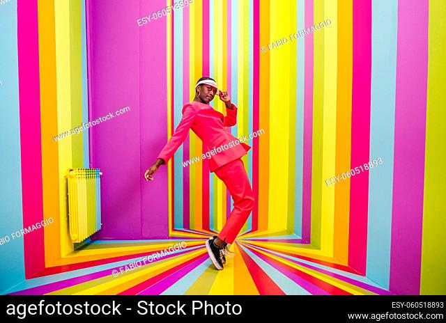 Beautiful african american young woman dancer having fun inside a rainbow box room - Cool and stylish afro adult woman portrait on multicolored background