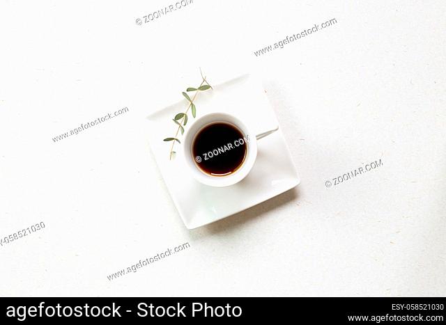 Cup of coffee with eucalyptus leaf on white background. top view, copy space