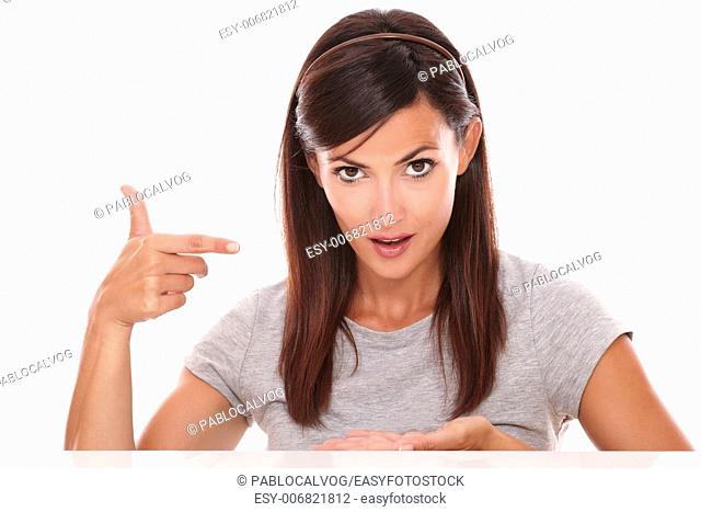 Portrait of pretty hispanic woman pointing to her palm up while looking at you on isolated studio - copyspace