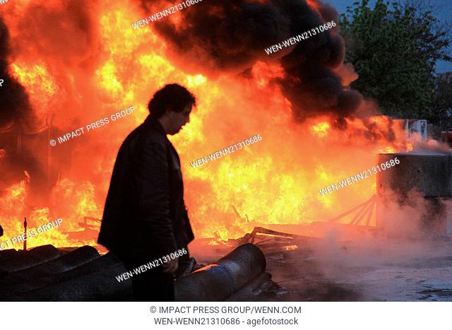 Firefighters try to locate a fire as people watch and take pictures of bon fire after a gas station explosion in the town of Vratca east of the Bulgarian...