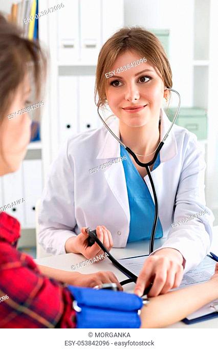 Smiling female medicine doctor measuring blood pressure to patient. Physical, medic shop or store, heart beat monitoring, cardio therapeutist assistance