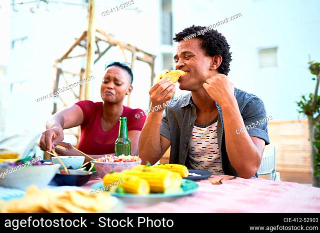 Young man eating taco lunch at patio table