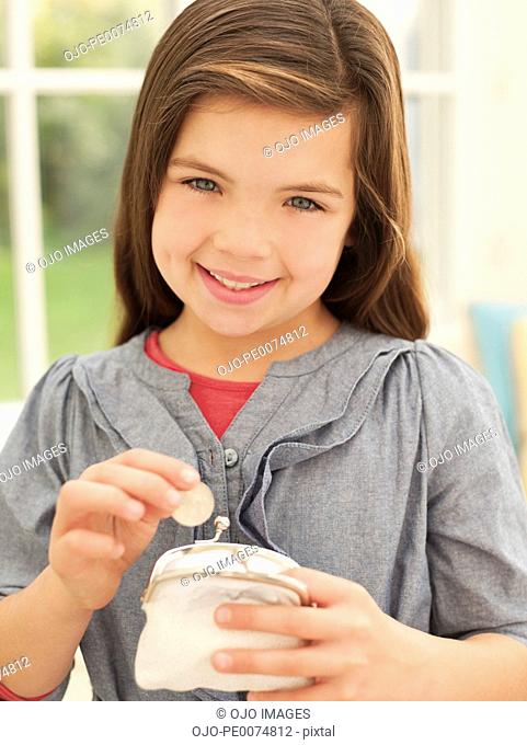 Smiling girl putting money into coin purse