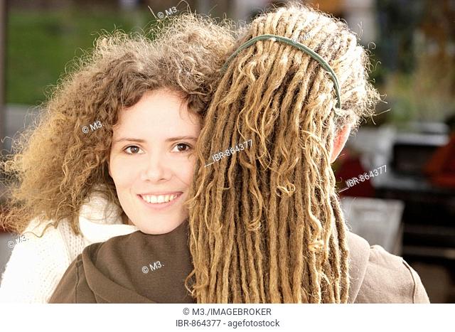 Woman with curly hair smiling and a man with dreadlocks