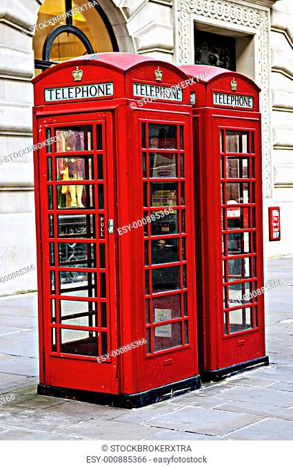 Two red telephone boxes near on London sidewalk
