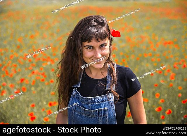 Smiling young woman standing in poppy field