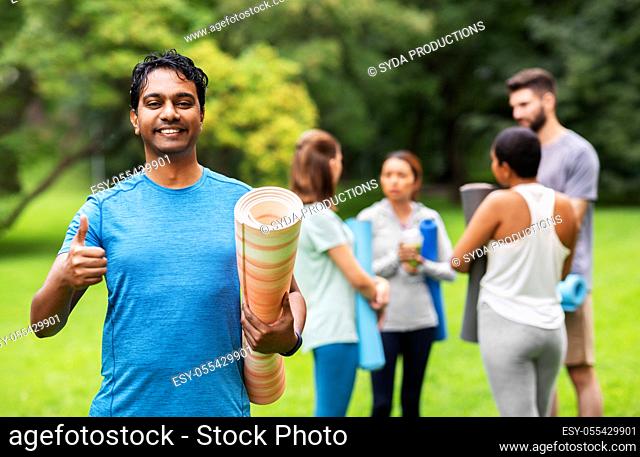 smiling indian man with yoga mat showing thumbs up