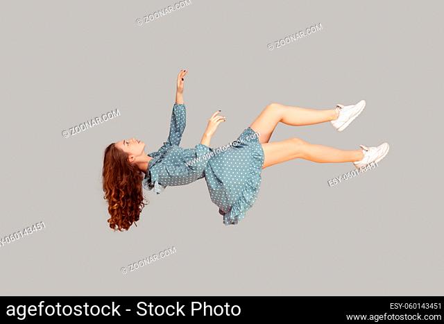 Floating in air. Relaxed girl in vintage ruffle dress levitating keeping eyes closed, sleeping while flying mid-air, having comfortable peaceful dream