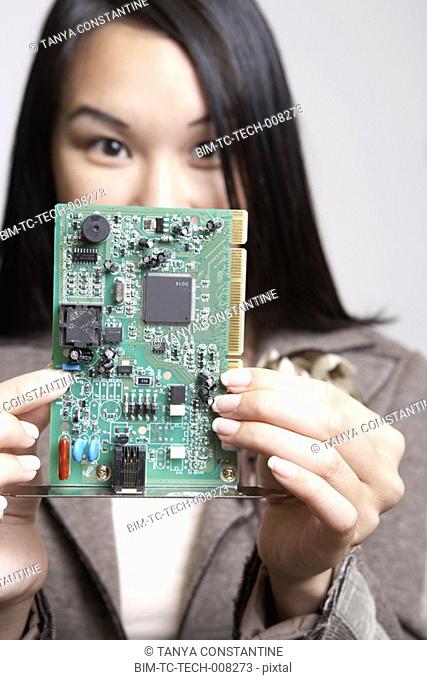 Asian businesswoman holding up computer circuit board