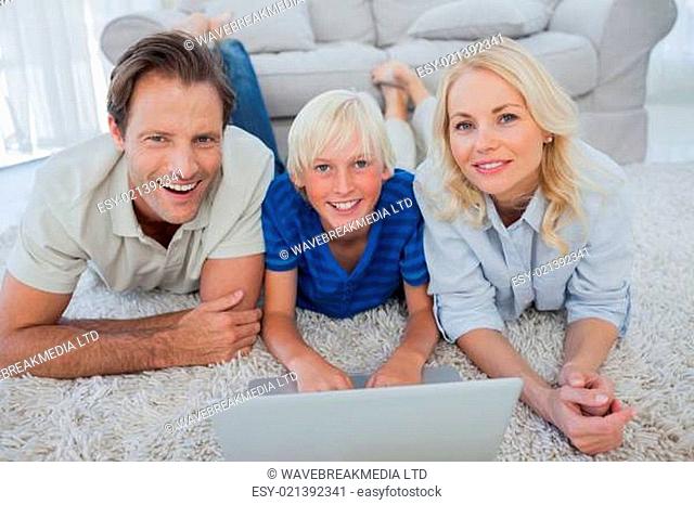 Portrait of son and parents using a laptop lying on a carpet
